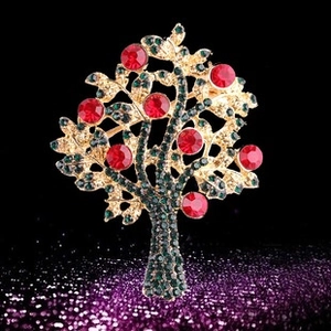Détail de la broche sapin de Noël en alliage doré avec cristaux verts et strass rouges