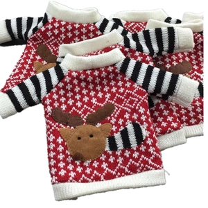 Close-up of knitted Christmas wine bottle covers with red elk and stripe patterns