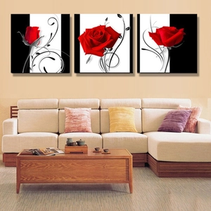 Three-piece red rose canvas wall art set hanging above a beige sofa in a modern living room