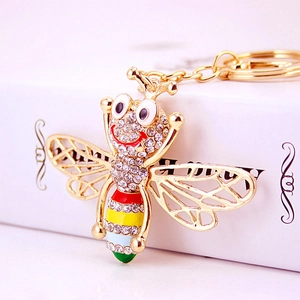Golden bee keychain with colorful rhinestones on a white gift box background