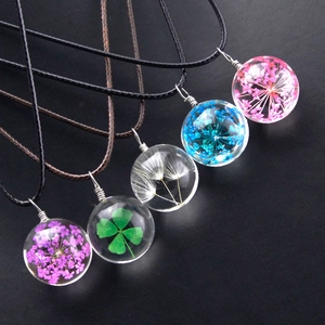 Detailed view of five unique dried flower glass ball pendants on woven cords