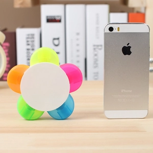 Flower-shaped highlighter with five vibrant colors on a wooden desk next to a phone