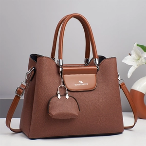 Détail de la texture en toile tissée marron et rabat en cuir d'un sac à main trapèze chic