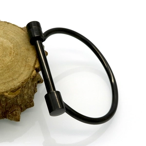Détail d'un manille en forme de D en métal noir sur un support en bois naturel
