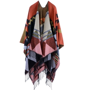 Close-up of geometric pattern knit poncho featuring long fringe trim and warm fabric texture