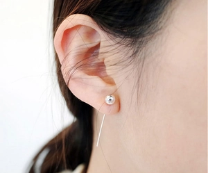 Close-up of minimalist 925 sterling silver ball stud earring with long tassel on model ear
