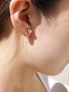 Close-up of a minimalist 925 silver earring with a sleek ball and long tassel needle bar