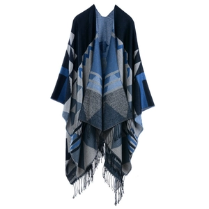 Detail of geometric knit shawl showing navy block patterns and long fringe tassels