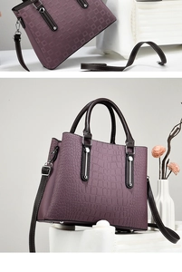 Detail of purple textured leather tote bag featuring brown handles and silver hardware