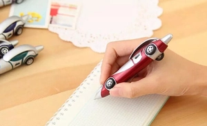 Action shot of red car-shaped ballpoint pen writing on paper over a wooden desk