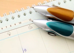 Macro detail of creative racing car-shaped ballpoint pens on a spiral notebook page