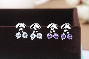 Detailed view of silver cherry stud earrings with sparkling white and purple gemstones