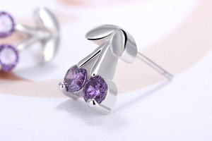 Macro shot of silver cherry stud earrings with purple cubic zirconia stones