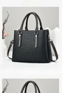 Front view of black crocodile pattern handbag with silver hardware and brown handles