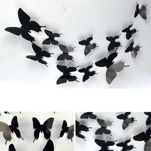 Macro detail of black 3D butterfly wall stickers showing flexible PVC wings on white wall