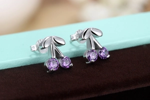 Macro shot of silver cherry earrings with purple crystals and sparkling cubic zirconia