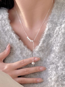 Detail view of S925 silver beaded necklace with dangling pearls on grey sweater