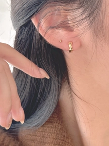 Close-up of minimalist gold plated 925 silver hoop earrings and ball stud on ear