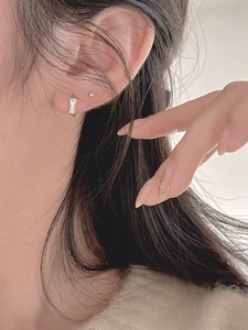Detailed view of minimalist 925 sterling silver stud earrings worn on ear lobe