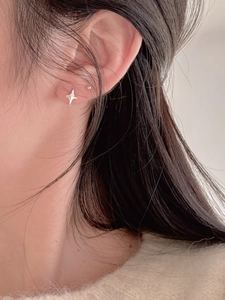 Vue macro d'une boucle d'oreille étoile en argent 925 et clou rond avec maille douillette