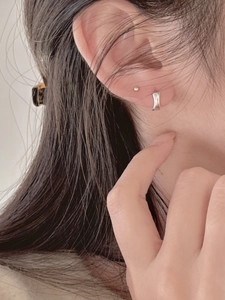 Close-up of minimalist polished silver ear cuff and ball stud earring set for women