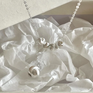 Macro shot of 925 silver Y-shape necklace with brushed metal beads on tissue paper