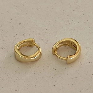 Minimalist thick gold hoop earrings in 925 sterling silver on stone background
