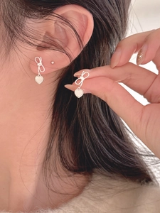 Detailed view of S925 silver bow stud earrings featuring white shell heart pendants