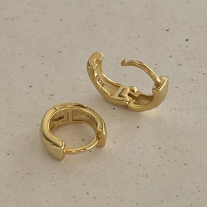 Close-up of golden wide huggie earring showing S925 hallmark on the polished inner band