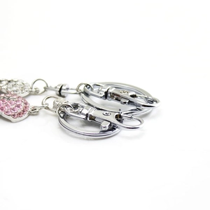 Close-up of silver metal keyrings with pink and clear rhinestones on a white background