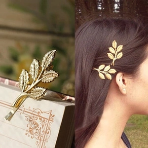 Detailed view of a golden leaf metal hair clip on a book and worn in hair