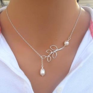 Detail of silver-plated leaf necklace with white pearls worn on a model with a white shirt