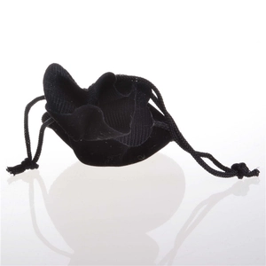 Detailed view of a soft black velvet drawstring pouch for jewelry on a white reflective surface