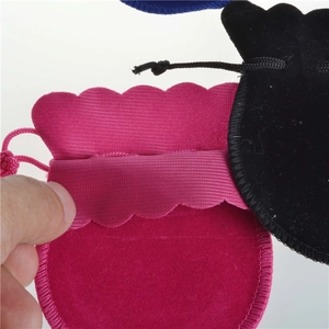 Detailed shot of small velvet drawstring pouches in pink, black, and blue colors