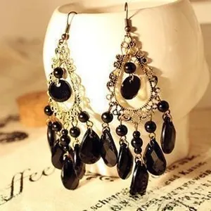 Detail of vintage ethnic long tassel earrings with black beads and gold filigree on a model