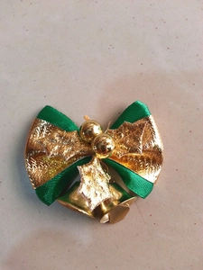 Macro detail of green ribbon Christmas bow with gold bells and festive holly leaf elements