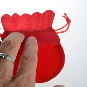 Close-up of hand opening a small red velvet drawstring jewelry pouch with wavy edge