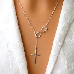 Close-up of a silver lariat necklace featuring infinity and cross pendants on a model