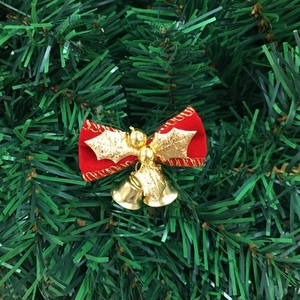 Detail of red velvet Christmas bow with gold bells and leaves on pine needles