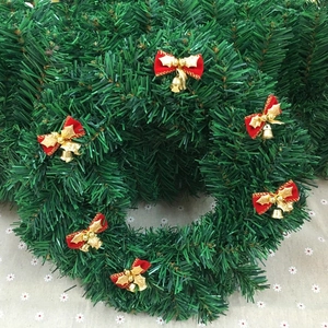 Close-up of artificial green Christmas wreath with red bows and small golden bells