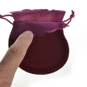 Close-up of small dark red velvet jewelry pouch with drawstring held in hand
