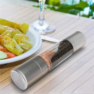 Close-up of dual stainless steel pepper and salt grinder mill on a dining table