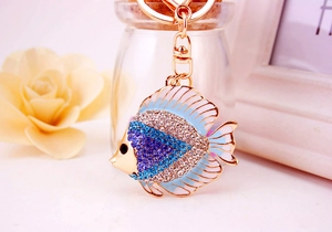 Macro detail of golden tropical fish keychain with blue rhinestones and white enamel