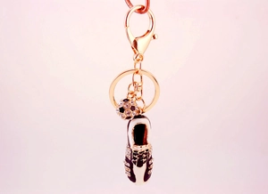 Detailed shot of golden keychain with sparkling rhinestone football and soccer shoe charms