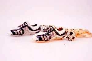 Close-up of golden football shoe and ball keyrings with rhinestones and enamel details