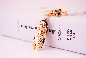 Close-up of golden soccer shoe keychain with a sparkling diamond-studded mini ball pendant