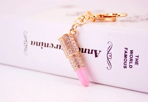 Macro shot of gold lipstick keychain with sparkling rhinestones and pink lipstick detail