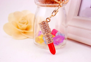 Detailed macro of a gold crystal lipstick keychain with red top and shiny rhinestones