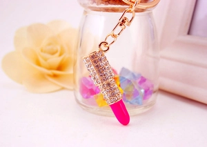 Detail shot of a sparkling rhinestone lipstick keychain with vibrant pink resin and gold metal