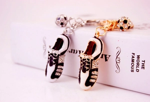 Close-up of diamond-studded football boot keychains in gold and silver finishes